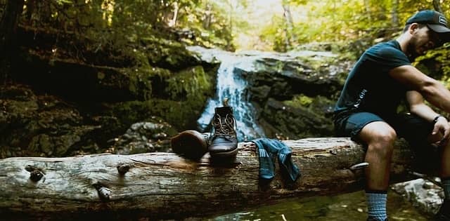 man resting on log with shoes and socks