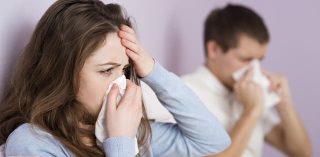 woman and man sneezing into tissues