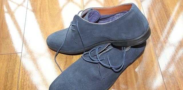 A pair of blue suede shoes on a hardwood floor