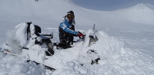 man stuck in the snow with snowmobile