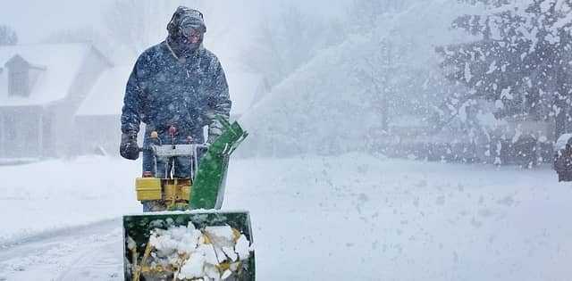 A man snow blowing his driveway